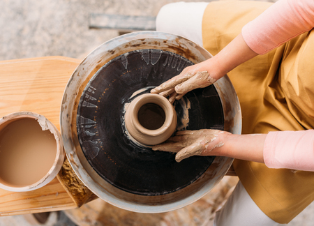 Cropped view of child making ceramic pot with clay on pottery wheelの写真素材