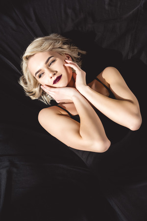 Attractive girl with makeup posing in elegant black dress for fashion shootの写真素材