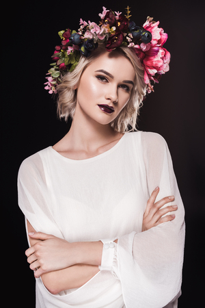 Attractive blonde girl posing in white dress and floral wreath, isolated on black backgroundの写真素材