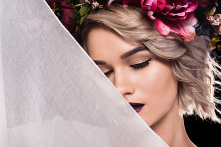Attractive girl posing in floral wreath with veil, isolated on black backgroundの写真素材
