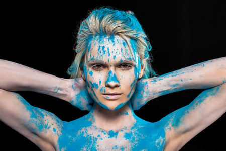 Young blonde woman in blue powder, isolated on black backgroundの写真素材