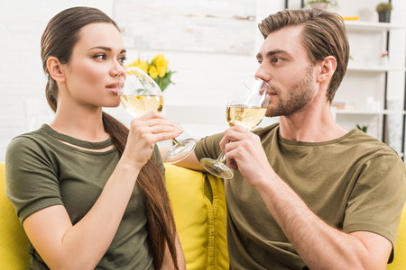 young couple drinking wine together on couch at homeの写真素材