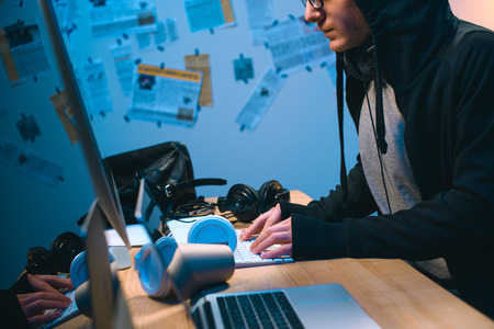 cropped shot of hooded young hacker working with computerの写真素材