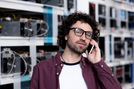 handsome computer engineer talking by phone at ethereum mining farm