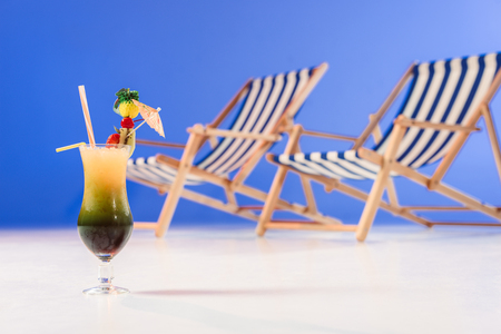 Cocktail in glass by deck chairs on blue backgroundの写真素材