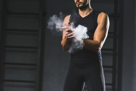 Cropped image of young sportsman spreading chalk powder in hands  in sports hallの写真素材