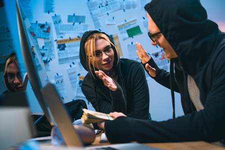 happy couple of hackers with stack of cash giving high fiveの写真素材