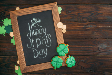close-up view of wooden frame with happy st patricks day inscription and golden coins on tableの写真素材