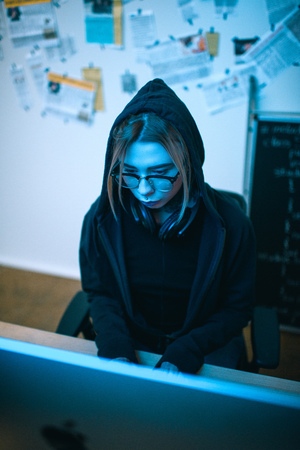 high angle view of young female hacker developing malware under blue lightの写真素材
