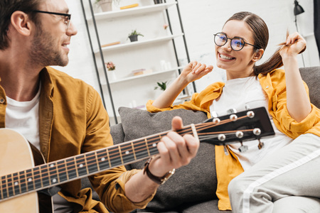 young man playing guitar for happy girlfriendの写真素材