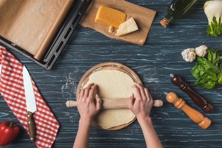 cropped image of woman rolling dough for pizza with rolling pinの写真素材