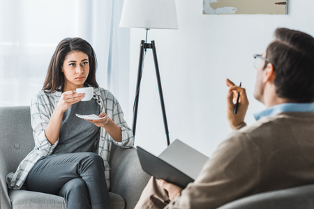 Woman drinking coffee and listening to male doctor recommendationsの写真素材