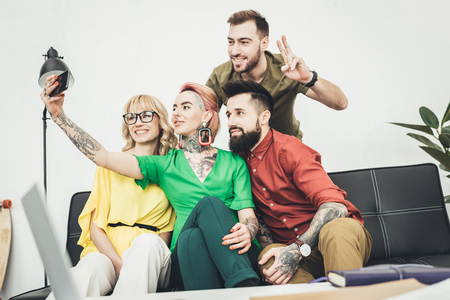 portrait of group of creative workers taking selfie on smartphone togetherの写真素材
