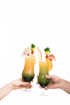 cropped view of couple holding glasses with summer cocktails, isolated on whiteの写真素材
