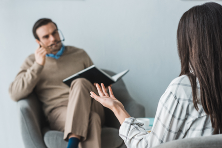Woman complaining about her health opposite to male doctor in officeの写真素材