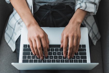 Close-up view of female hands typing on laptop keyboard