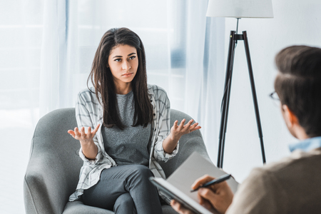 Woman complaining to male psychotherapist in doctor officeの写真素材