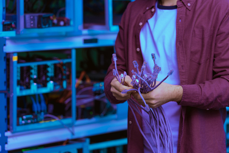 cropped shot of computer engineer with LAN wires at ethereum mining farm