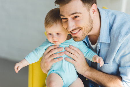 Young father holding infant daughter in handsの写真素材