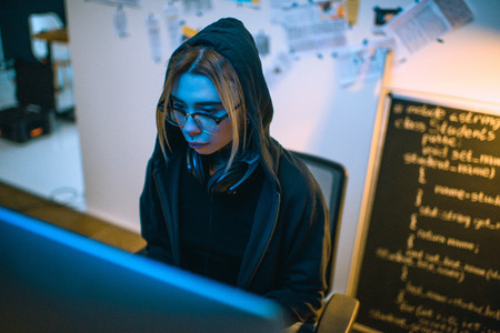high angle view of female hacker developing malware under blue lightの写真素材