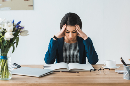 Tired businesswoman looking at notebook on office tableの写真素材