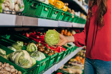 partial view of shopper choosing fresh raw cabbage in hypermarketの写真素材