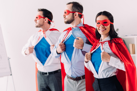 super businesspeople in masks and capes showing blue shirts in office