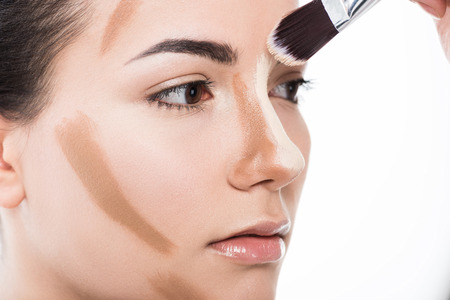 cropped image of visagiste doing makeup for girl isolated on whiteの写真素材