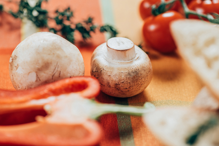 selective focus of fresh ripe mushrooms and cherry tomatoes on tableの写真素材