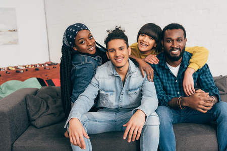 smiling group of young multiethnic friends embracing each other on couch
