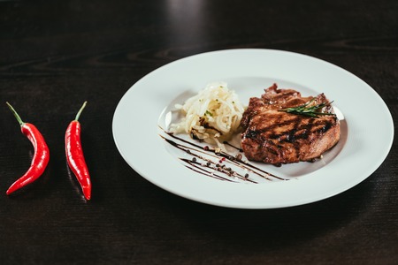 delicious grilled juicy steak with rosemary and chilli peppers on tableの写真素材