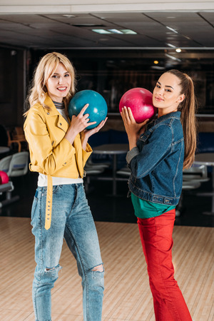 attractive young woman holding colorful balls at bowling clubの写真素材