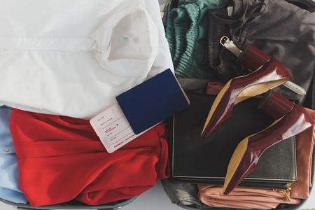 top view of opened travel bag with clothes, heels and ticket with passportの写真素材