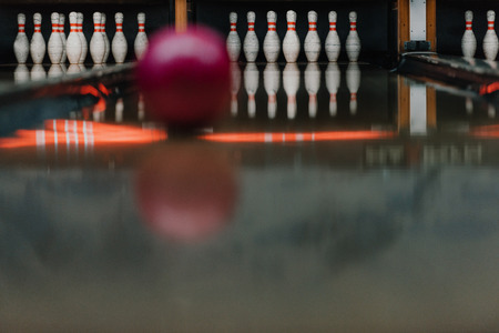 red bowling ball rolling to pins by alleyの写真素材