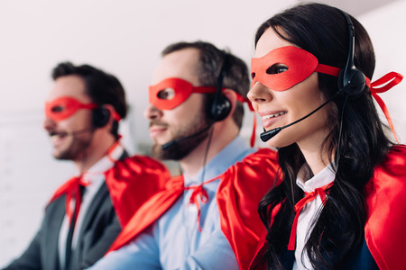 super businesspeople in masks and headsets supporting customers in call centerの写真素材