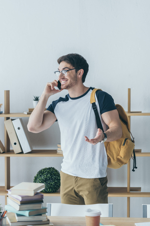happy male student with backpack talking on smartphoneの写真素材
