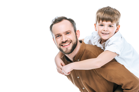 happy father piggybacking little son and smiling at camera isolated on whiteの写真素材