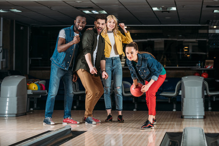 excited group of young friends playing bowling togetherの写真素材