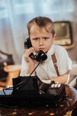 cute little boy holding handset and looking at camera, 1950s styleの写真素材