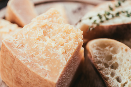 close-up view of gourmet parmesan cheese and slices of fresh bread on wooden cutting board