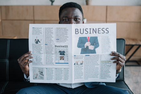 obscured view of african american businessman with newspaper in cafeの写真素材