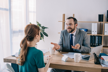 businessman and client discussing contract during meeting in officeの写真素材