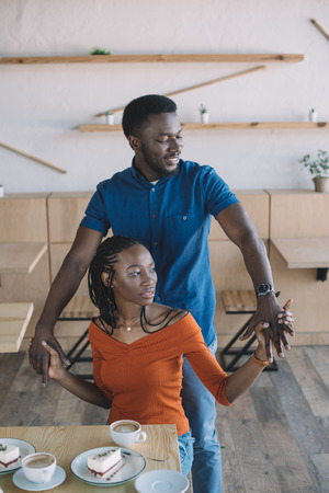 smiling african american couple holding hands on romantic date in coffee shopの写真素材