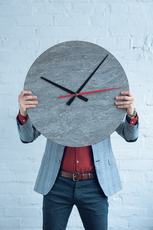 Man holding large clock in front of his face