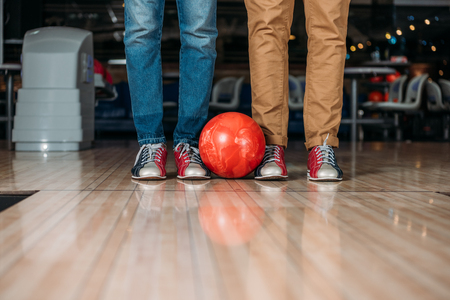 cropped shot of men standing in front of bowling alley with ballの写真素材