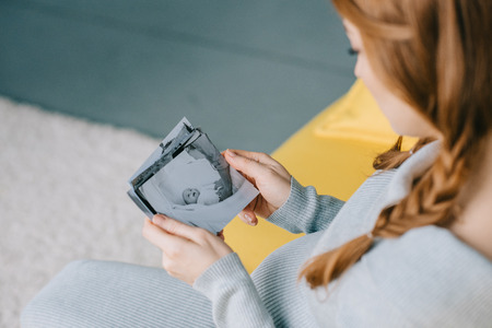 cropped image of pregnant woman holding photo of newborn baby in living roomの写真素材