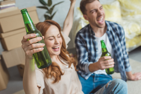 young happy couple with bottles of beer at new apartment, relocation conceptの写真素材