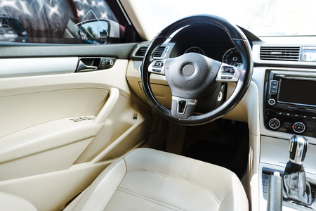 Cropped image of black steering wheel and beige leather seats new car on streetの写真素材