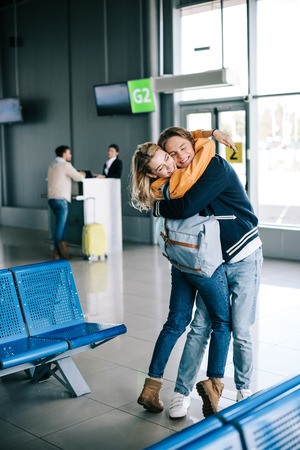 Happy young couple of travelers hugging in airport terminalの写真素材