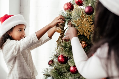 Partial view of African American woman and kid decorating Christmas tree together at homeの写真素材